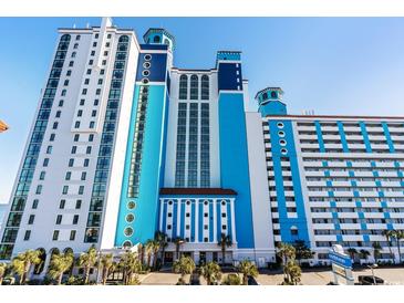 A multi-story resort with a bright blue and white exterior, palm trees, and well-maintained landscaping at 3000 N Ocean Blvd. N # 129, Myrtle Beach, SC 29577