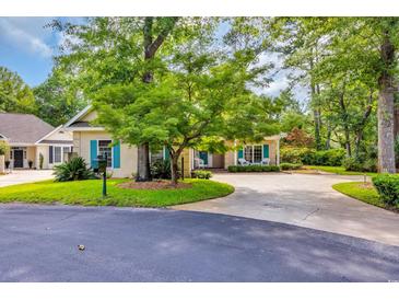 Charming home features manicured lawn and a circular driveway, surrounded by mature trees at 444 Dornoch Dr., Pawleys Island, SC 29585