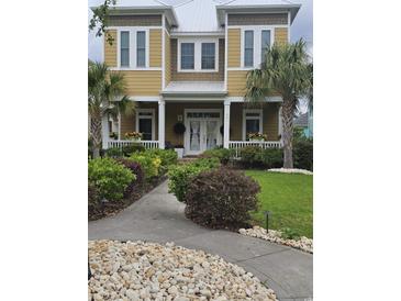 Charming two-story home with a landscaped yard, inviting front porch, and classic architectural details at 451 W Palm Dr., Myrtle Beach, SC 29579
