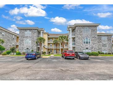 Beautiful multi-story condo building with stone accents and manicured landscaping, located next to parking area at 4705 Wild Iris Dr. # 305, Myrtle Beach, SC 29577