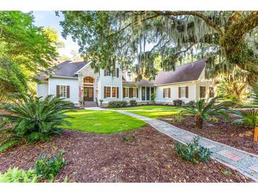 Stately two-story home with stone accents, lush landscaping, and a grand entryway framed by a mature oak tree at 509 Heston Point Dr., Pawleys Island, SC 29585