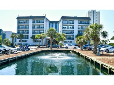 Beautiful waterfront condo complex with palm trees and a fountain in the foreground, offering serene views and coastal charm at 5905 South Kings Hwy. # 116B, Myrtle Beach, SC 29575