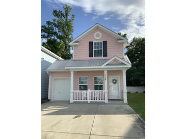 Charming pink two-story home with a front porch, white railings, and a well-maintained lawn at 739 Shell Creek Circle # 739, North Myrtle Beach, SC 29582