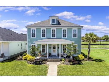 Charming two-story home with a welcoming front porch, well-manicured lawn, and beautiful landscaping at 1106 Tarpon Pond Rd., North Myrtle Beach, SC 29582