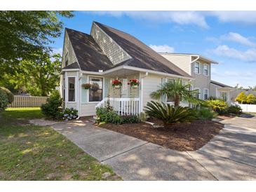 Charming exterior featuring a well-maintained lawn and colorful flowering plants on the porch at 1422 Baldwin Ct. # 1422, Little River, SC 29566