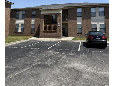 Brick building exterior with parking spaces in front on a sunny day at 2005 Greens Blvd. # F-205, Myrtle Beach, SC 29577