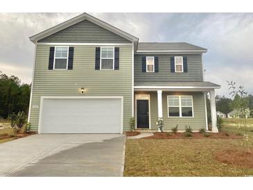 Two-story home with green siding, black shutters, white garage door, and manicured lawn at 292 Clear Lake Dr., Conway, SC 29526