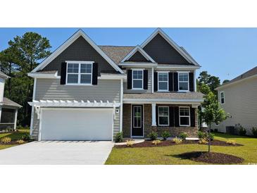 Charming two-story home with stone accents, neutral siding, a two-car garage, and manicured landscaping at 720 Rupert Dr, Conway, SC 29526