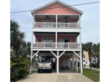 Charming three-story beach house with double balconies and covered parking nestled amongst lush palms at 124 Rainbow Dr., Murrells Inlet, SC 29576