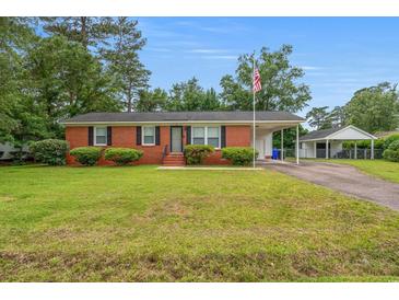 Charming brick home featuring manicured lawn, carport, and an American flag, perfect curb appeal at 203 Longwood Ln., Conway, SC 29527