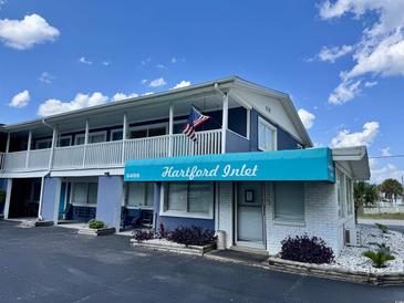 Two-story building exterior featuring a balcony, blue awning, and an American flag at 5409 North Ocean Blvd. # 106/7108, North Myrtle Beach, SC 29582