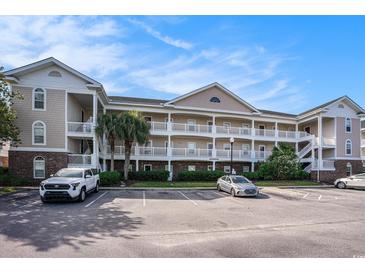 Three-story condo building with a beautiful facade, exterior staircases, and a well-kept parking area under a bright blue sky at 5751 Oyster Catcher Dr. # 315, North Myrtle Beach, SC 29582