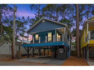 Charming blue two-story coastal home on stilts with a spacious front porch and dusk sky at 6001 - 1737 S Kings Hwy., Myrtle Beach, SC 29575