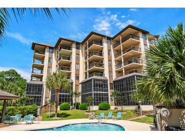 Beautiful multi-story building with balconies and a pool surrounded by lush greenery and palm trees at 310 73Rd Ave. N # 5B, Myrtle Beach, SC 29572