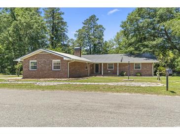 Charming brick ranch home with a metal roof and well-maintained front yard at 1043 South Main St., Aynor, SC 29511