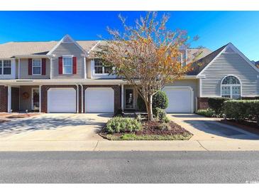Charming townhouse featuring a one-car garage, manicured landscaping, and neutral siding, radiating curb appeal at 107 Pawleys Place Dr. # 107, Pawleys Island, SC 29585