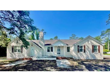 Charming, white brick home showcasing multiple entryways, a chimney, and classic design details at 401 S Nichols St., Nichols, SC 29581