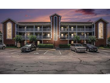 Condo building with balconies and parking in front showing dusk sky with peach and purple colors at 4853 Meadowsweet Dr. # 1805, Myrtle Beach, SC 29579