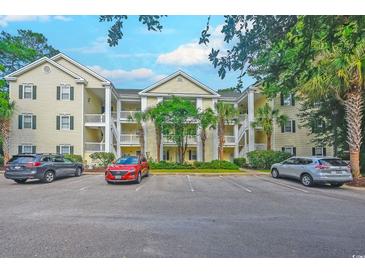 Inviting condominium complex with yellow siding, white trim, palm trees, and ample parking at 601 N Hillside Dr. # 4434, North Myrtle Beach, SC 29582
