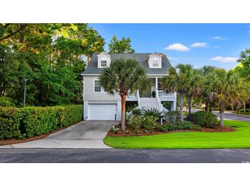 Charming two-story home with a well-manicured lawn, lush greenery, and a welcoming front porch at 12 Jerry Ct., Pawleys Island, SC 29585