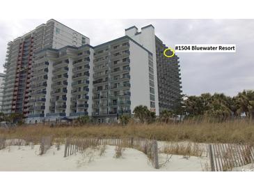 Exterior shot of the condominium building at Bluewater Resort with beach vegetation in the foreground at 2001 S Ocean Blvd. # 1504, Myrtle Beach, SC 29577