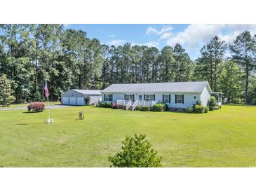 Ranch-style home boasts a manicured lawn, detached garage, and covered front porch, perfect for relaxing at 203 Warbler St., Georgetown, SC 29440