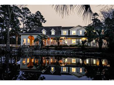 Stunning exterior view with water reflection, mature trees, and a charming facade, creating a serene and inviting atmosphere at 2790 Fowler Rd., Loris, SC 29569