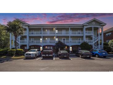 Three-story condo building with white balconies and stairs, and multiple parked cars at 3939 Gladiola Ct. # 202, Myrtle Beach, SC 29588