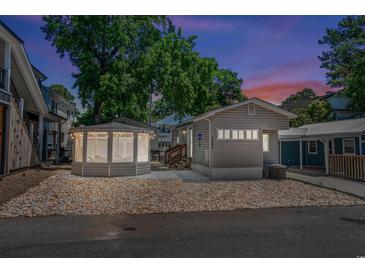 Charming home featuring a gazebo, gray siding, rock landscaping, and well-lit exterior for evening appeal at 6001 - 1842 S Kings Hwy., Myrtle Beach, SC 29575