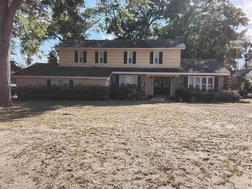 Traditional two-story home featuring a symmetrical facade, classic shutters, and a landscaped front yard with mature trees at 903 23Rd Ave. N, North Myrtle Beach, SC 29582