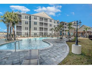 Beautiful community pool with lounge chairs and palm trees at a condo complex under a blue sky with white clouds at 150 Ella Kinley Circle # 301, Myrtle Beach, SC 29588