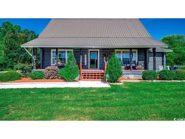 Charming log cabin-style home with a metal roof, landscaped front yard, and inviting porch at 181 Halfway Rd., Nichols, SC 29581
