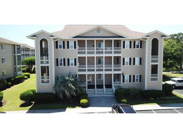 A beige three-story condo building featuring white railings, black shutters, and manicured landscaping at 1900 Duffy St. # L-5, North Myrtle Beach, SC 29582