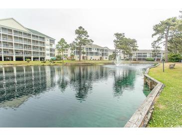 Scenic pond view with fountain and condominium buildings in the background under a cloudy sky at 305 N Hillside Dr. # 206, North Myrtle Beach, SC 29582