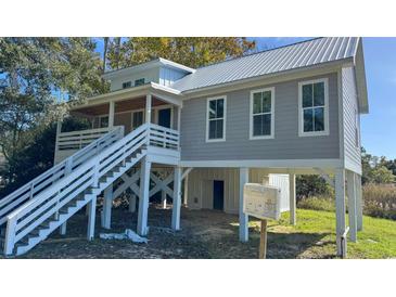 Lovely home exterior boasts a metal roof, large staircase, and gray siding at Tbd Park St., Georgetown, SC 29440