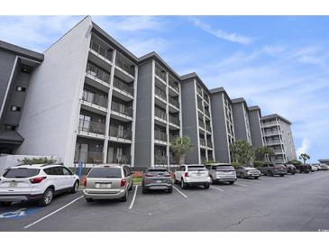 Multi-story condo building with grey exterior, balconies, parking lot, and blue sky at 5905 South Kings Hwy. # A518, Myrtle Beach, SC 29575
