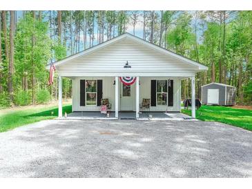 Charming single story house with a covered front porch and gravel driveway surrounded by lush trees at 67 Bossie Ln., Georgetown, SC 29440