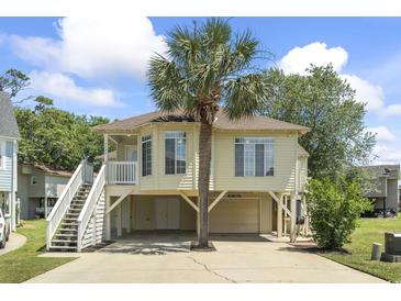 Charming raised beach house with a palm tree, covered parking, and inviting staircase leading to the front porch at 914 Dock Pl., Murrells Inlet, SC 29576