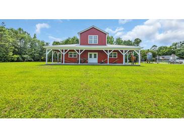 Charming red barn-style home with a white-columned porch and expansive green lawn at 1039 Forest Dr., Conway, SC 29526