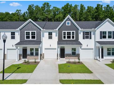Charming townhomes showcasing a blend of gray and white exteriors, complemented by lush greenery and private driveways at 776 Nw Palm Frond Way # 55, Calabash, NC 28467