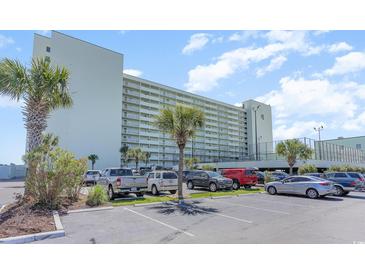 Multi-story condominium building with ample parking and a view of palm trees on a sunny day at 9400 Shore Dr. # 124, Myrtle Beach, SC 29572