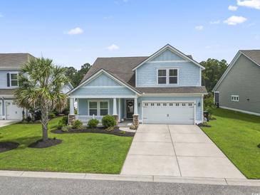 Charming two-story home with a manicured lawn, a two-car garage, and a welcoming front porch at 223 Southgate Ct., Pawleys Island, SC 29585