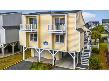 Inviting yellow exterior featuring double balconies, elevated design, and stylish staircase entry at 39 Newport St., Ocean Isle Beach, NC 28469