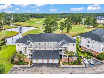 Scenic aerial view of condo complex overlooking a golf course and a pond, featuring a parking area at 4811 Orchid Way # 301, Myrtle Beach, SC 29577