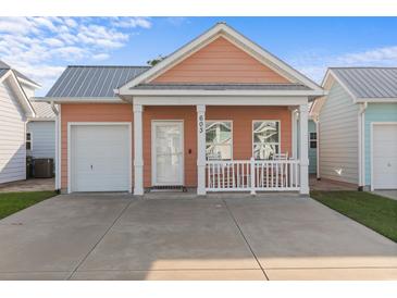 Charming peach-colored home featuring a metal roof, a quaint front porch, and an attached garage at 603 Wave Rider Ln. # 603, North Myrtle Beach, SC 29582