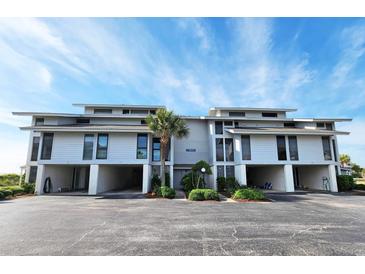 Three-story condo building with covered parking, lush landscaping, and a picturesque palm tree at 701 Norris Dr., Pawleys Island, SC 29585