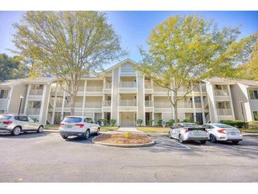 Three-story condo building featuring parking and mature landscaping and trees on a sunny day at 1550 Spinnaker Dr. # 3123, North Myrtle Beach, SC 29582