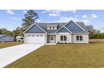 Charming home with a two-car garage, gray roof, and blue and beige siding, set on a well-maintained lawn at 1900 Blue Bird Rd., Loris, SC 29569