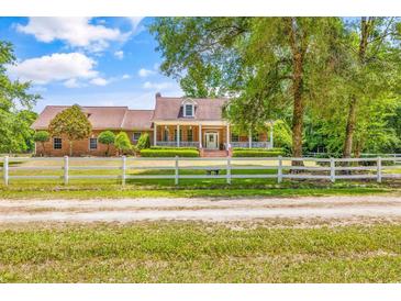 Charming brick home featuring a welcoming front porch and a manicured lawn with a white fence at 1961 Bright Rd., Little River, SC 29566