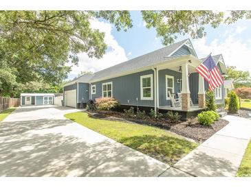 Charming home with a rocking chair front porch, an American flag, and a detached garage with a fenced yard at 2588 Long Avenue Ext., Conway, SC 29526